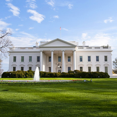 The White House from the from with a water fountain feature and green lawns in front of it.