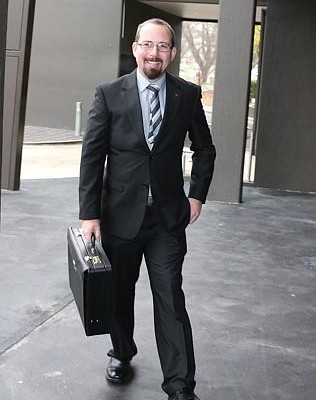 Senator Ricky Muir looking professional in a suit and holding a briefcase.